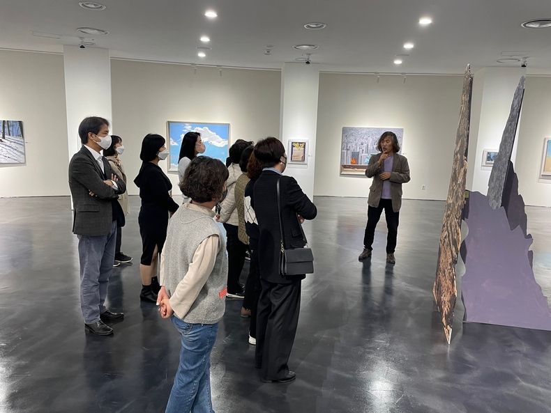  한국을 대표하는 중견작가 김영구 Kim, Young-Gu 화백이 전시장을 찿은 관람객들에게 작품 설명을 하고 있다. (사진제공=김영구화백)