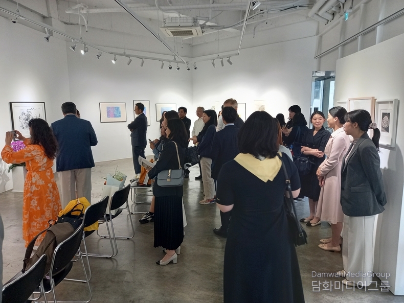 A number of visitors admire artworks by Filipino artist Lenore RS Lim.