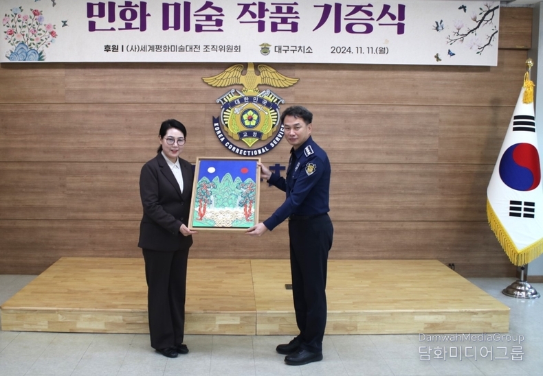 사단법인 세계평화미술대전 조직위원회 민화분과 위원장 이미형(명지대 교수)가 대구 구치소 김영광 소장에게 작품을 기증하고 있다.