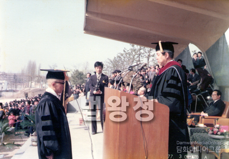 이 사진은 초대법왕 일붕 서경보 큰스님께서 박사학위를 수여받는 역사적인 순간을 담고 있습니다. 뒤편에는 불자들과 관계자들이 자리하여 이 뜻깊은 장면을 함께 축하하고 있으며, 스님의 오랜 학문과 수행의 공덕이 공식적으로 인정받는 장면으로, 『세계일화』의 한 장면처럼 깊은 감동을 줍니다.