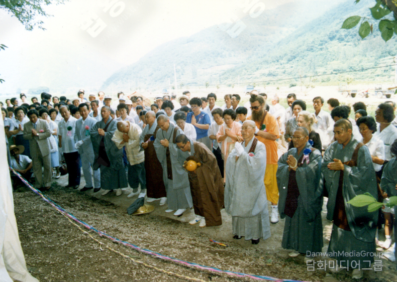 초대법왕 <strong>일붕 서경보 큰스님</strong>을 중심으로, <strong>한국의 승려들</strong>과 더불어 <strong>해외 스님들과 외국인 불자들</strong>이 나란히 합장하고 있으며, 이는 <strong>불교의 국경 없는 자비정신</strong>과 <strong>세계평화를 향한 공통의 염원</strong>을 상징합니다.