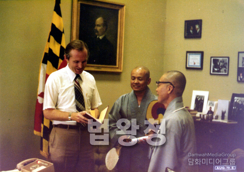 사진은 초대 법왕 일붕 서경보 큰스님께서 1979년 8월, 미국 메릴랜드 주청사(Maryland State House)를 방문해 주정부 관계자와 공식적인 만남을 갖는 장면을 담고 있습니다. 스님께서는 전통적인 선물인 태극선太極扇과 서예 작품을 직접 전달하며, 불교의 평화정신과 한국의 문화적 가치를 전하고 계십니다. 이는 단순한 외교 의례가 아닌, 문화 외교·진리 외교의 실천으로서, 당시 한국 불교의 국제화와 평화포교의 구체적인 모습을 보여주는 소중한 기록입니다. 배경에 걸린 메릴랜드 주기州旗와 미국 정치인의 초상화, 그리고 벽에 걸린 다양한 사진과 감사장 등이 공식적인 외교 방문임을 뒷받침해주며, 스님의 평화와 통일, 인류 화합을 위한 세계적 여정의 한 장면으로 기억됩니다.