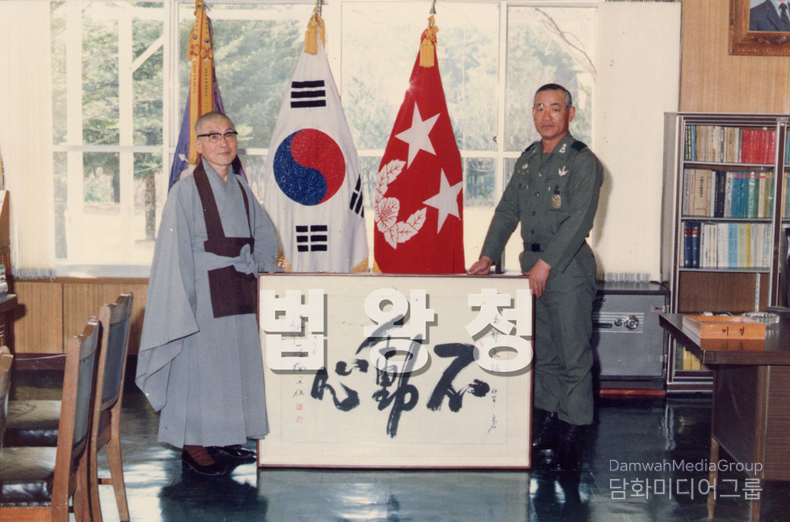 사진 속 작품의 휘호는 초대 법왕 일붕 서경보一鵬 徐京保 스님께서 남기신 「不動心」부동심입니다. 이에 대한 작품 설명은 아래와 같습니다. 즉. 불변의 마음, 흔들림 없는 중심 「不動心」은 ‘흔들리지 않는 마음’, 즉 모든 외부의 유혹이나 혼란, 두려움 앞에서도 중심을 잃지 않는 정신을 뜻합니다. 선禪 사상에서 ‘부동심’은 수행자의 핵심 덕목으로, 온갖 번뇌와 마주하더라도 마음이 요동하지 않고 고요히 머무는 상태를 가리킵니다. 일붕 스님의 이 휘호는 단순한 정신 수양의 경지를 넘어서, 불법佛法의 실천과 포교, 나아가 국가와 민족을 위한 대의 앞에서도 흔들리지 않는 결심을 상징합니다. 특히 군부대에 이 작품을 기증한 맥락에서, 이는 장병들에게 강건한 정신력과 올곧은 충의忠義의 정신을 일깨우는 메시지로도 읽힙니다.