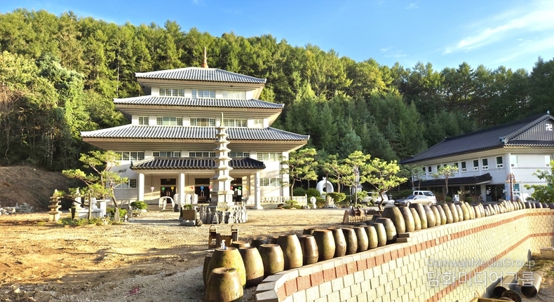 푸른 산자락을 배경으로 천년 향화의 기운이 서린 벽사초불정사 전경, 층층이 겹쳐 올라간 기와지붕과 정면에 우뚝 선 석탑은 불법의 중심을 드러내며, 옹기 담장과 소나무 정원은 전통과 생명의 숨결을 담아낸다. 이곳은 자손이 없어도 향불이 꺼지지 않는 천년향화지지千年香火之地로, 제사·추모·기도·예술이 공존하는 새로운 시대의 명당으로 자리하고 있다.